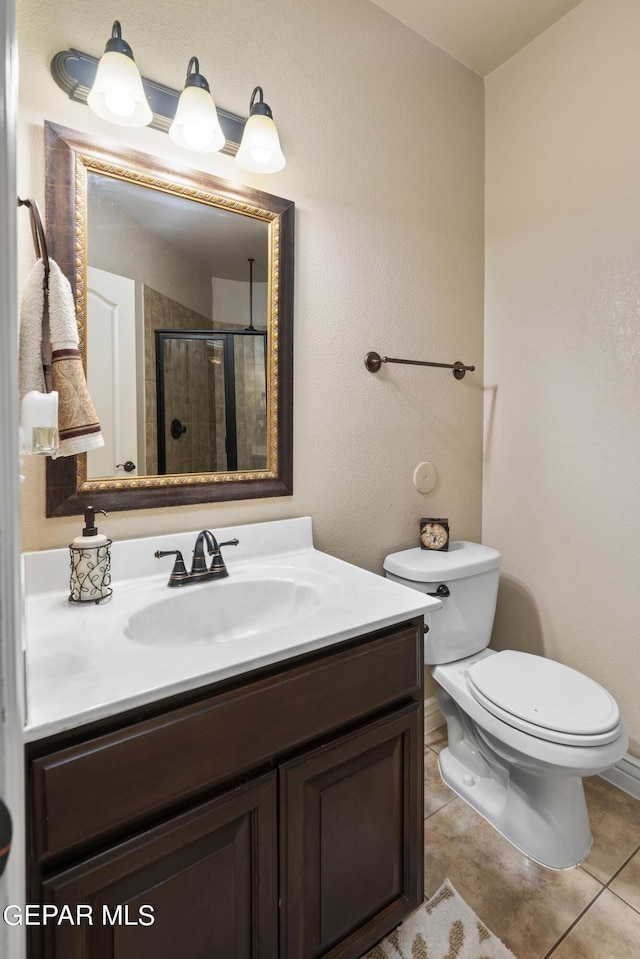 bathroom with toilet, tile patterned flooring, a shower with shower door, and vanity