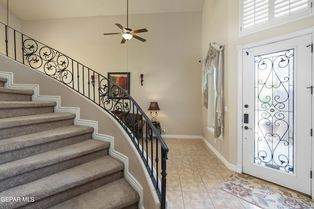 foyer featuring ceiling fan, plenty of natural light, light tile patterned floors, and a towering ceiling