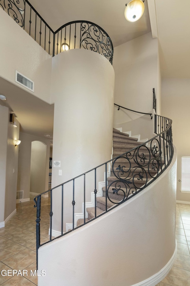 staircase with a high ceiling and tile patterned floors