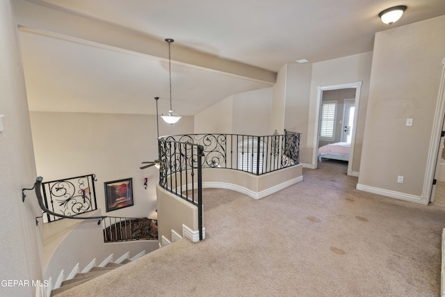 stairs with carpet floors and beamed ceiling