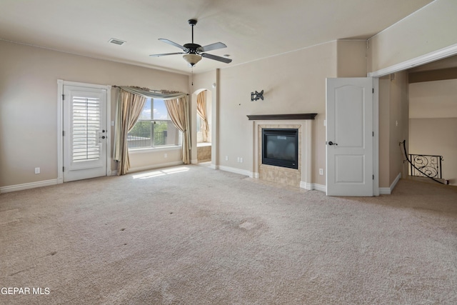 unfurnished living room with light carpet, a tiled fireplace, and ceiling fan