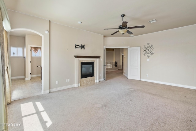 unfurnished living room with ceiling fan, light carpet, and a tiled fireplace