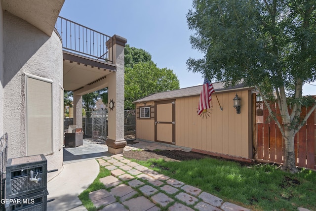 view of yard featuring a patio, a balcony, and a shed