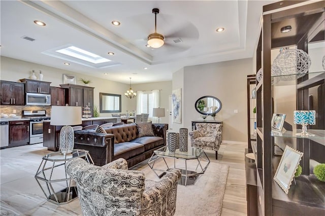 1701 Bull Ring St, El Paso, TX 79928 - living room with ceiling fan with notable chandelier, light wood-type flooring, a tray ceiling, and a skylight