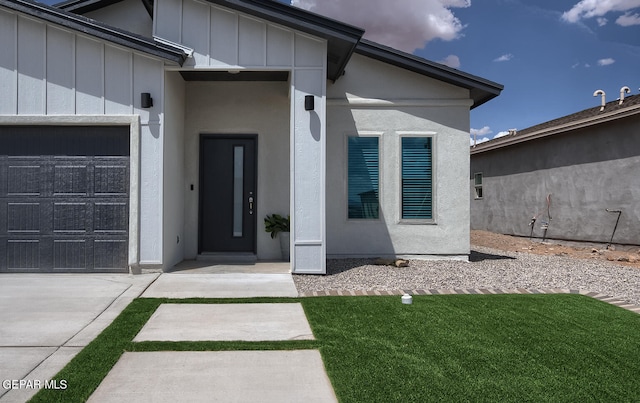 doorway to property with a garage and a lawn