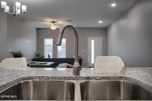 details featuring light stone countertops, sink, a notable chandelier, and decorative light fixtures