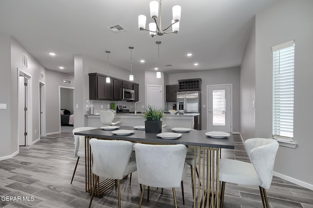 kitchen featuring appliances with stainless steel finishes, dark brown cabinets, sink, and decorative light fixtures