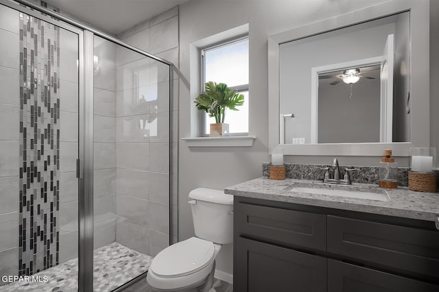 bathroom featuring vanity, ceiling fan, a shower with shower door, and toilet