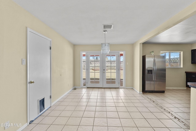 unfurnished dining area featuring a chandelier, light tile patterned floors, french doors, and a wealth of natural light