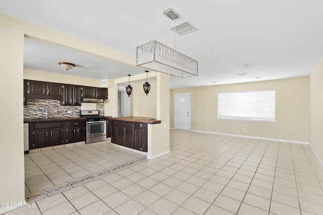 kitchen with hanging light fixtures, decorative backsplash, light tile patterned floors, dark brown cabinetry, and stainless steel range with gas stovetop