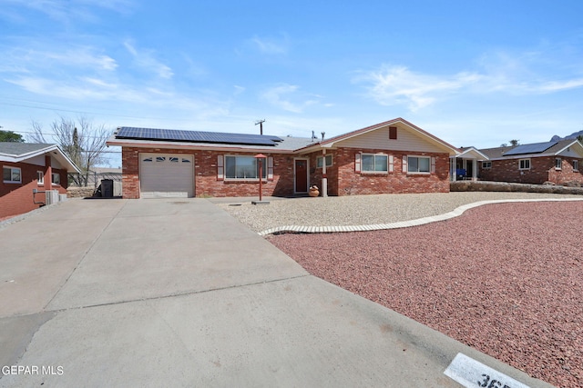 ranch-style house with a garage and solar panels