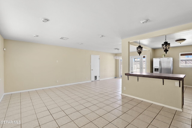 interior space featuring a breakfast bar, french doors, stainless steel refrigerator with ice dispenser, light tile patterned flooring, and kitchen peninsula