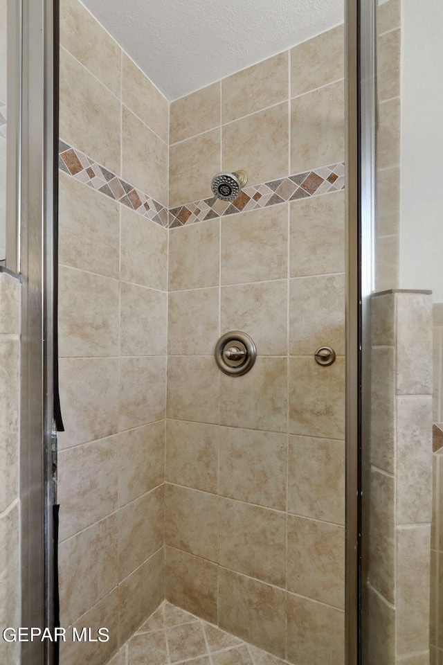 bathroom with tiled shower and a textured ceiling