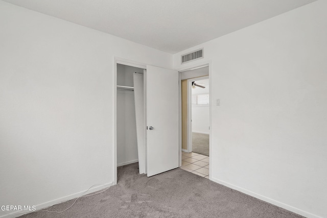 unfurnished bedroom featuring light colored carpet and a closet