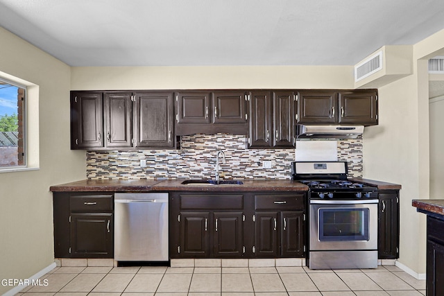 kitchen with decorative backsplash, dark brown cabinets, stainless steel appliances, sink, and light tile patterned floors