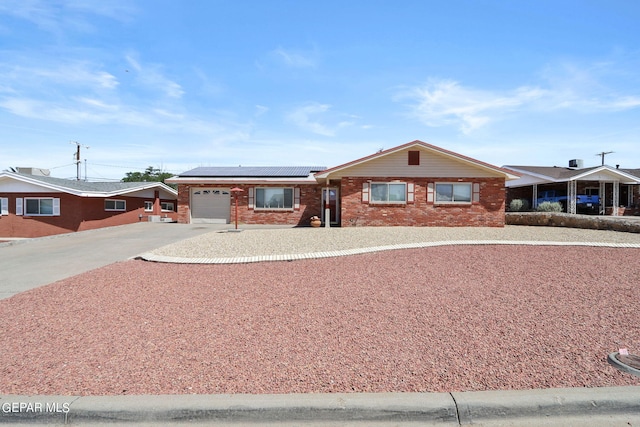 ranch-style house with a garage and solar panels