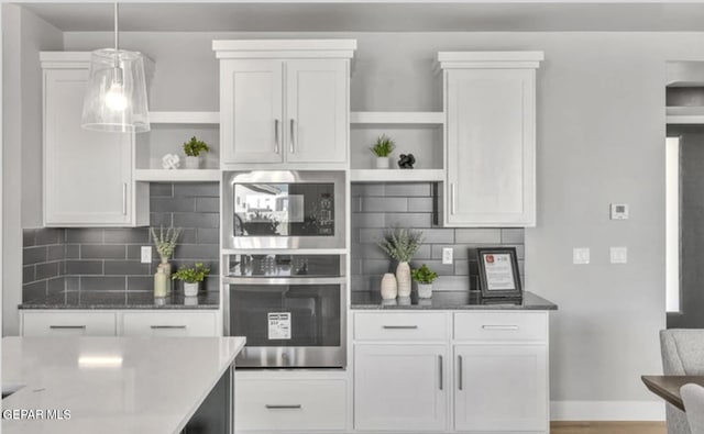 kitchen with black microwave, stainless steel oven, white cabinets, and tasteful backsplash