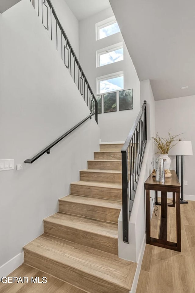 staircase featuring wood-type flooring and a towering ceiling