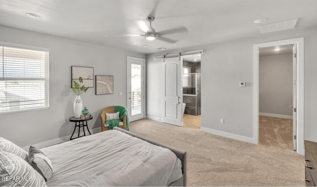 carpeted bedroom with ensuite bathroom, ceiling fan, and a barn door