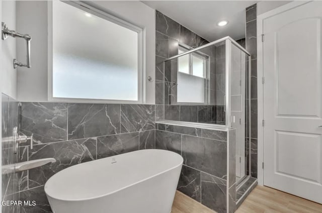 bathroom featuring plenty of natural light, tile walls, hardwood / wood-style flooring, and separate shower and tub