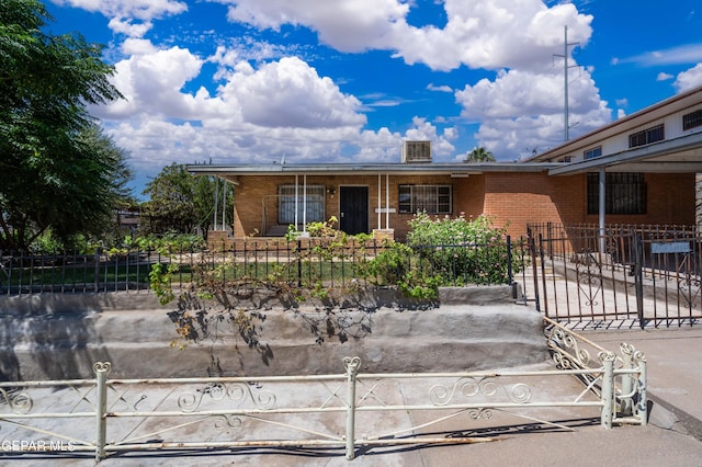 ranch-style home with a fenced front yard and brick siding