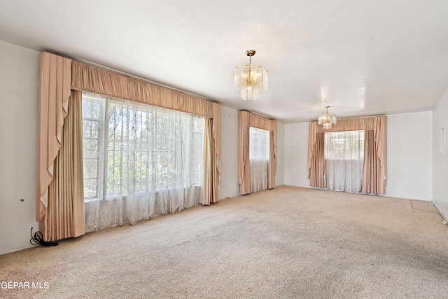 spare room featuring carpet floors and a notable chandelier