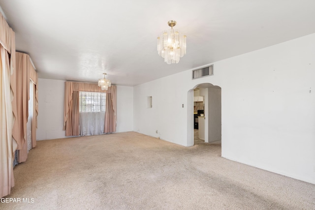 unfurnished room with arched walkways, light carpet, visible vents, and a notable chandelier