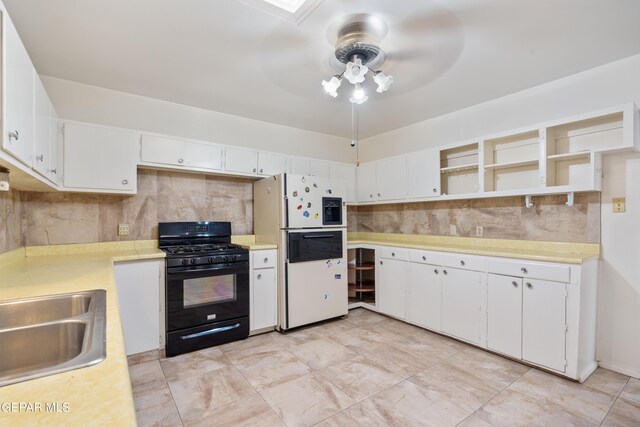 kitchen with white cabinetry, sink, ceiling fan, black gas stove, and white fridge