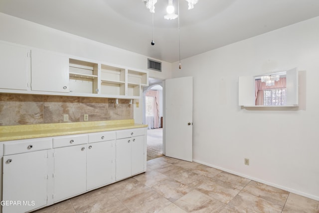 kitchen with arched walkways, open shelves, light countertops, and visible vents