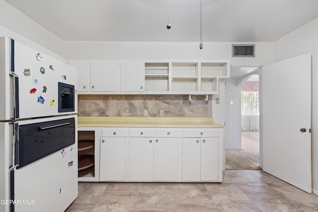 kitchen featuring arched walkways, freestanding refrigerator, light countertops, and open shelves