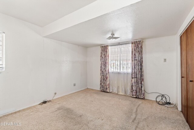 unfurnished room with carpet flooring and a textured ceiling