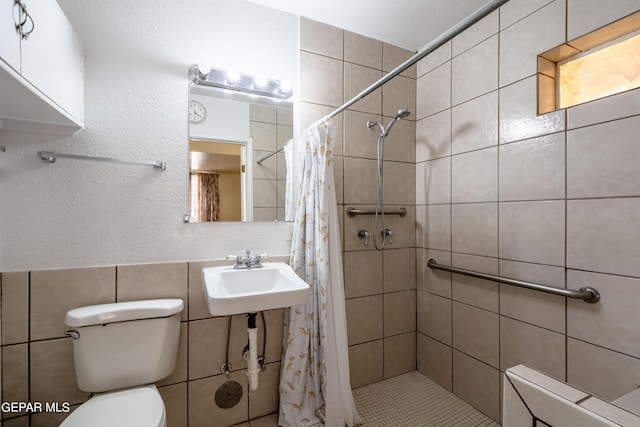 full bath featuring tile walls, a sink, toilet, and a shower stall