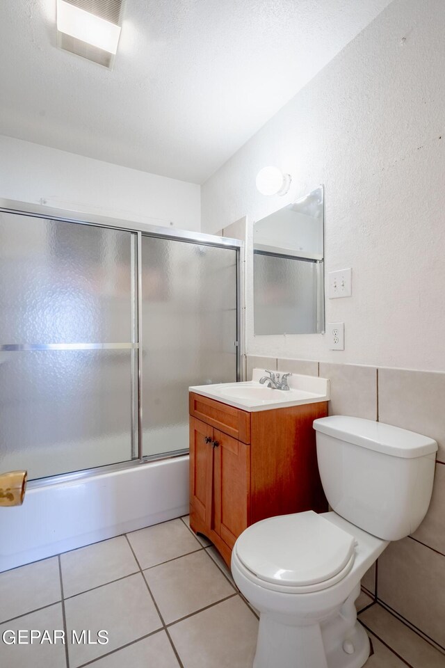 full bathroom featuring tile patterned flooring, vanity, bath / shower combo with glass door, and toilet