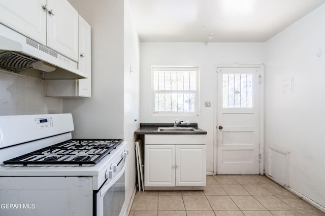 kitchen with white gas range, white cabinetry, sink, and light tile patterned flooring