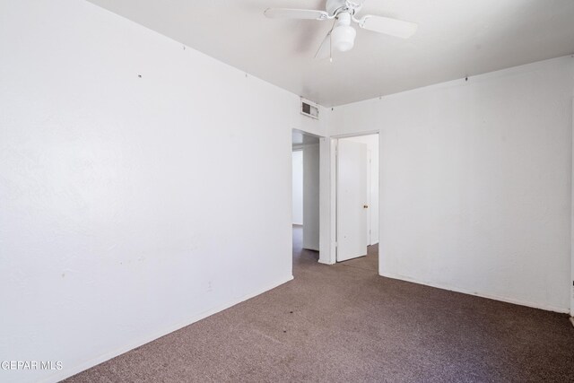 spare room featuring dark colored carpet and ceiling fan