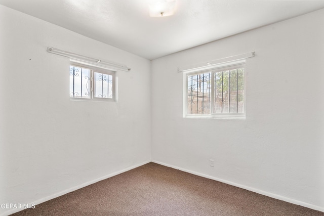 carpeted spare room featuring plenty of natural light and baseboards