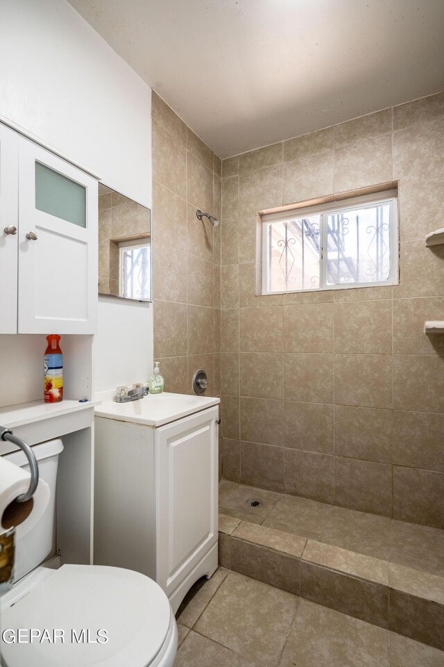 bathroom with a tile shower, toilet, and tile patterned floors