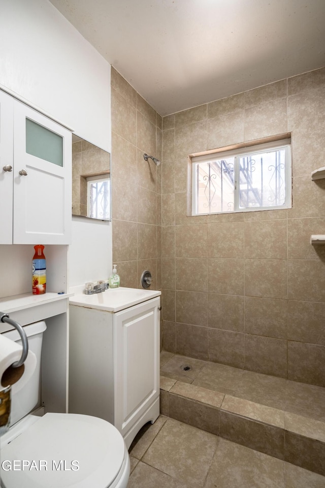 full bath featuring a sink, tiled shower, tile patterned flooring, and toilet