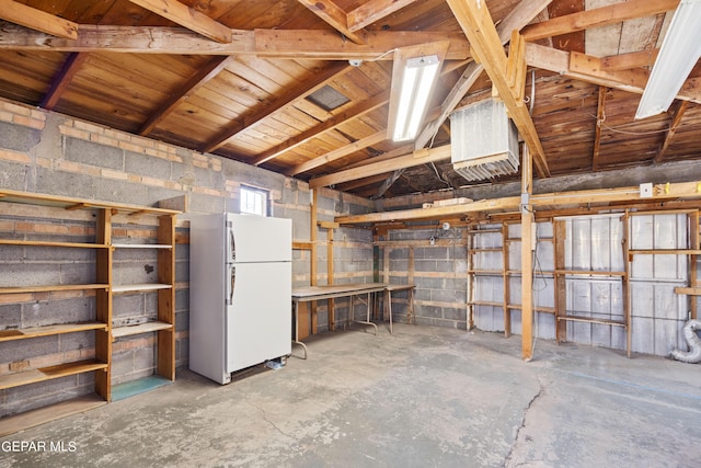 basement with freestanding refrigerator and concrete block wall