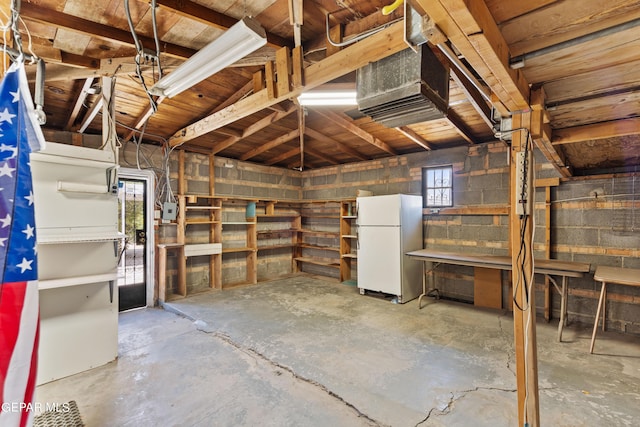 below grade area with concrete block wall and freestanding refrigerator