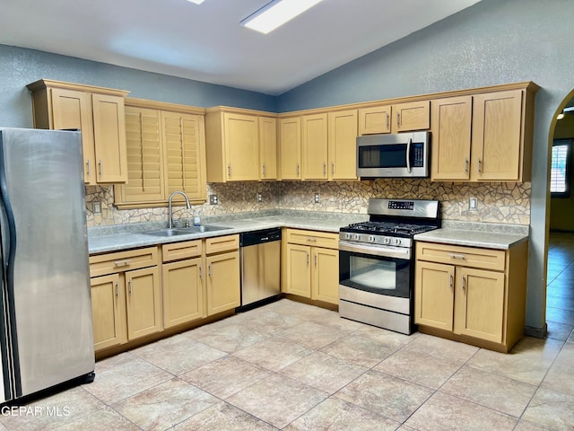 kitchen with appliances with stainless steel finishes, backsplash, vaulted ceiling, and sink