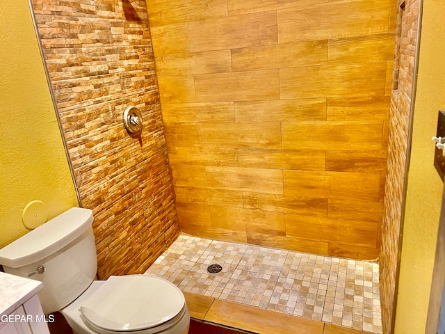 bathroom with tiled shower, vanity, and toilet