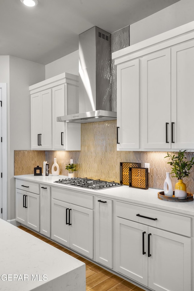 12741 Eltham Dr, Horizon City, TX 79928 - kitchen with stainless steel gas cooktop, light wood-style floors, wall chimney range hood, light countertops, and tasteful backsplash