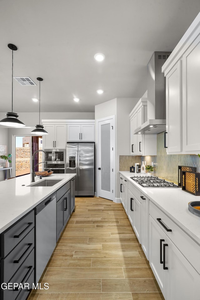 12741 Eltham Dr, Horizon City, TX 79928 - kitchen featuring visible vents, appliances with stainless steel finishes, a sink, white cabinets, and wall chimney exhaust hood