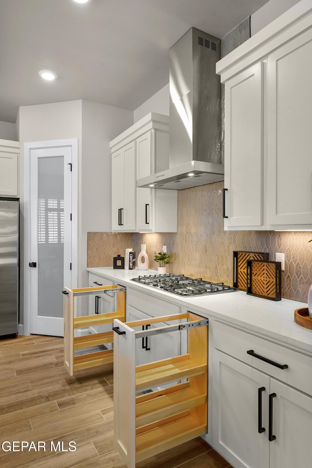 12741 Eltham Dr, Horizon City, TX 79928 - kitchen with decorative backsplash, light countertops, wall chimney exhaust hood, white cabinetry, and appliances with stainless steel finishes