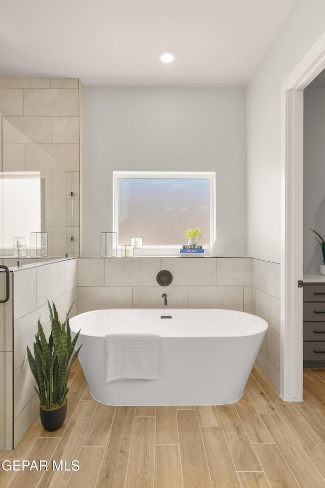 12741 Eltham Dr, Horizon City, TX 79928 - full bath with a freestanding bath, wood finished floors, and tile walls