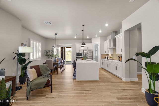 12741 Eltham Dr, Horizon City, TX 79928 - kitchen with white cabinets, appliances with stainless steel finishes, light countertops, wall chimney exhaust hood, and visible vents