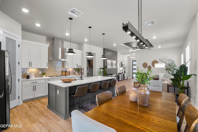 12741 Eltham Dr, Horizon City, TX 79928 - kitchen with visible vents, light countertops, wall chimney exhaust hood, and open floor plan