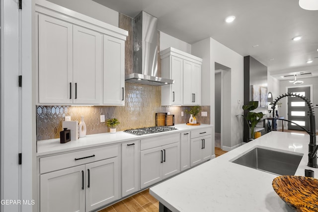12741 Eltham Dr, Horizon City, TX 79928 - kitchen featuring wall chimney range hood, tasteful backsplash, a sink, light wood-style flooring, and stainless steel gas stovetop