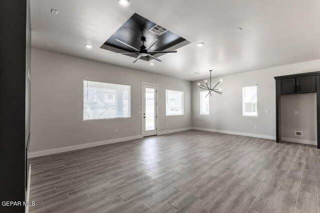 unfurnished living room featuring ceiling fan with notable chandelier and hardwood / wood-style flooring